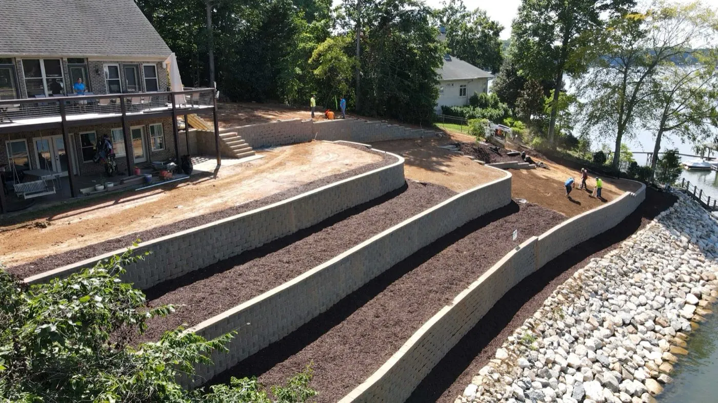 Crew installing tiers of a block retaining wall on a lakefront bank